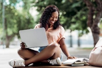 technology, education and people concept - happy smiling african american student girl with laptop computer and books in city. african student girl with laptop and books in city