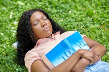 education, school and people concept - sleeping african american student girl with math textbook lying on grass. african student girl with book sleeping on grass