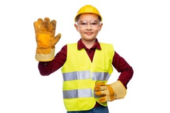 building, construction and profession concept - little boy in protective helmet, gloves, goggles and safety vest over white background. boy in protective helmet, gloves and safety vest