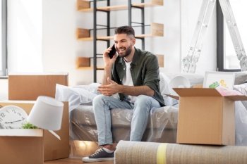 moving, people and real estate concept - happy smiling man with boxes calling on smartphone at new home. happy man calling on smartphone moving to new home