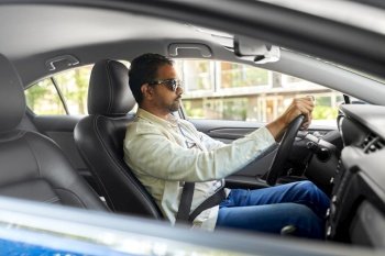 transport, vehicle and people concept - indian man or driver in sunglasses driving car. indian man or driver in sunglasses driving car