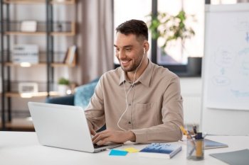 distant education, school and remote job concept - happy smiling male teacher with laptop computer and wireless earphones working at home office. teacher with laptop and earphones working at home