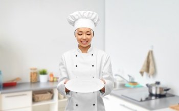 cooking, culinary and people concept - happy smiling female chef holding empty plate over kitchen background. happy smiling female chef holding empty plate