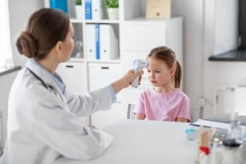 medicine, healthcare and pediatry concept - female doctor or pediatrician measuring little girl patient’s temperature with infrared forehead thermometer at clinic. female doctor and little girl patient at clinic