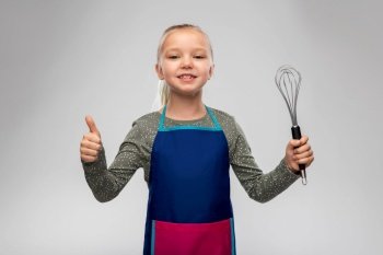 cooking, culinary and profession concept - happy smiling little girl in apron holding whisk showing thumbs up over grey background. little girl in apron with whisk showing thumbs up