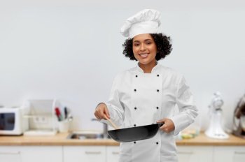 food cooking, culinary and people concept - happy smiling female chef with frying pan over kitchen background. smiling female chef with frying pan in kitchen