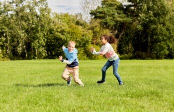 childhood, leisure and people concept - happy children playing tag game and running at park. happy children playing and running at park