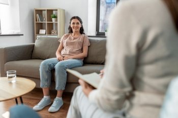 psychology, mental health and people concept - happy smiling young woman patient and woman psychologist at psychotherapy session. woman and psychologist at psychotherapy session