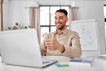 distance education, school and remote job concept - happy smiling male teacher with laptop computer having online class at home office showing thumbs up. teacher with laptop having online class at home
