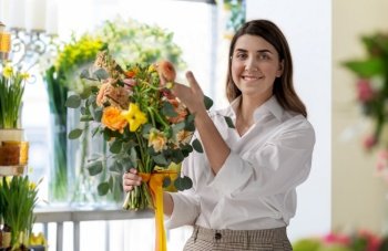 people, gardening and floral design concept - happy smiling woman or floral artist with bunch of flowers over shop background. happy woman with bunch at flower shop