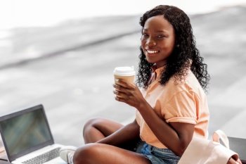 technology, education and people concept - happy smiling african american student girl with takeaway coffee cup and laptop computer in city. african student girl with coffee cup and laptop