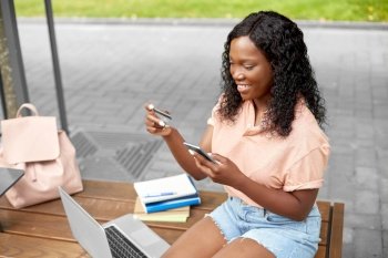 technology, education and people concept - happy smiling african american student girl with smartphone and credit card in city. student girl with smartphone and credit card