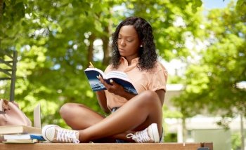 education, school and people concept - african american student girl with pencil making notes in book in city. african student girl making notes in book