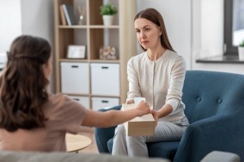 psychology, mental health and people concept - psychologist giving paper tissues to crying woman patient at psychotherapy session. psychologist and woman at psychotherapy session
