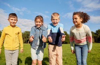 childhood, leisure and people concept - multiethnic group of happy kids showing thumbs up at park. happy children showing thumbs up at park
