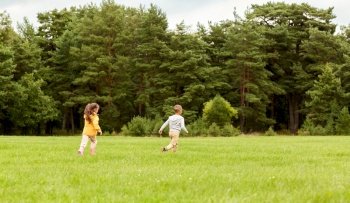 childhood, leisure and people concept - children playing tag game and running at park. children playing and running at park