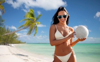 travel, tourism and summer holidays concept - happy smiling young woman in bikini swimsuit posing with volleyball over tropical beach background in french polynesia. woman in bikini posing with volleyball on beach