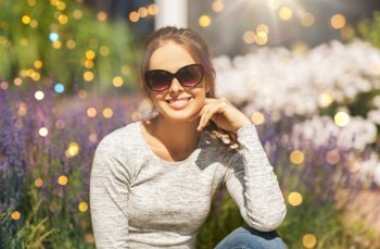 summertime, leisure and people concept - happy young woman in sunglasses at summer garden. happy young woman in sunglasses at summer garden