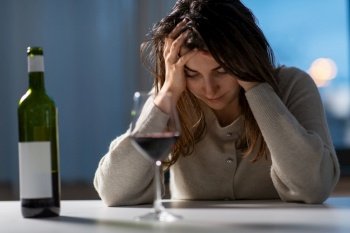 alcoholism, alcohol addiction and people concept - drunk woman or female alcoholic drinking red wine at home. woman alcoholic drinking red wine at home