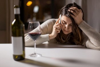 alcoholism, alcohol addiction and people concept - angry drunk woman or female alcoholic drinking red wine and calling on smartphone at home. woman alcoholic drinking wine and calling on phone