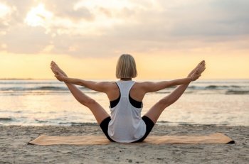 fitness, sport, and healthy lifestyle concept - woman doing yoga balancing bear pose on beach over sunset. woman doing yoga balancing bear pose on beach