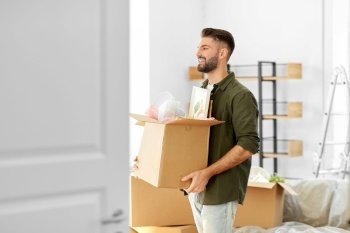 moving, people and real estate concept - happy smiling man holding box with stuff at new home. happy man with box moving to new home