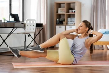 sport, fitness and healthy lifestyle concept - smiling teenage girl exercising on yoga mat at home. happy teenage girl exercising on yoga mat at home