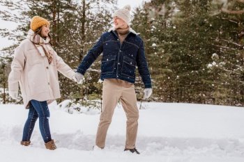 people, love and leisure concept - happy smiling couple walking in winter forest. happy smiling couple walking in winter forest