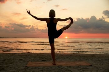fitness, sport, and healthy lifestyle concept - woman doing yoga hand-to-toe pose on beach over sunset. woman doing yoga hand-to-toe pose on beach