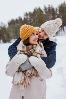 people, love and leisure concept - happy smiling couple hugging in winter park. happy smiling couple hugging in winter park