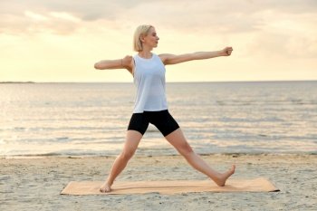 fitness, sport, and healthy lifestyle concept - woman doing yoga archer pose on beach over sunset. woman doing yoga archer pose on beach