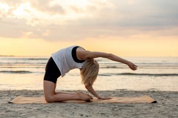 fitness, sport, and healthy lifestyle concept - woman doing yoga camel pose on beach over sunset. woman doing yoga camel pose on beach