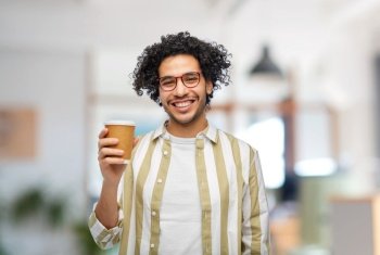 drinks and people concept - smiling young man in glasses with takeaway coffee cup over office background. smiling man with takeaway coffee cup at office
