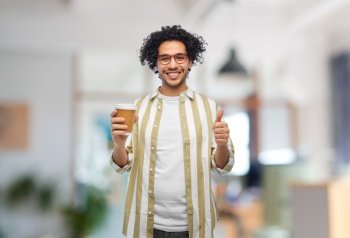 drinks and people concept - smiling young man in glasses with takeaway coffee cup showing thumbs up over office background. man with coffee cup showing thumbs up at office