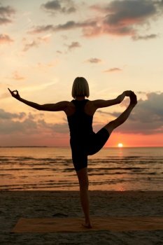 fitness, sport, and healthy lifestyle concept - woman doing yoga hand-to-toe pose on beach over sunset. woman doing yoga hand-to-toe pose on beach