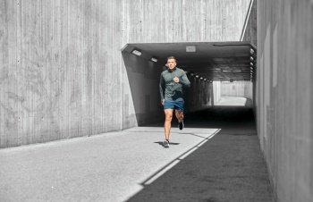 fitness, sport and healthy lifestyle concept - young man running out of tunnel. young man running out of tunnel