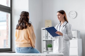 medicine, healthcare and people concept - female doctor with clipboard talking to woman patient at hospital. doctor with clipboard and woman at hospital