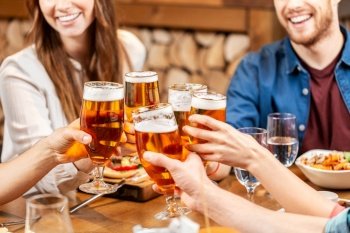 leisure, people and celebration concept - close up of happy friends having dinner and drinking beer at restaurant or pub. happy friends drinking beer at restaurant