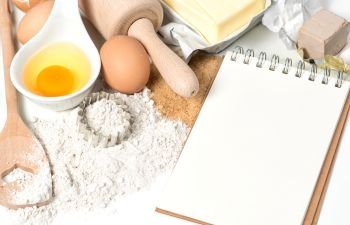 Food background. Recipe book and baking ingredients eggs, flour, sugar, butter, yeast. 