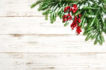 Christmas background. Evergreen tree branches with red berries decoration on wooden texture