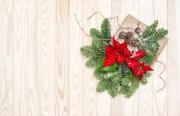 Christmas decoration. Pine branches, wrapped gift and poinsettia flowers on wooden background