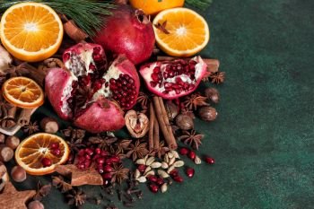 Fruits pomegranate and orange with spices and ingredients for mulled wine cinnamon, star anise, cardamon, nutmeg