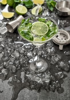 Cocktail with lime, mint and ice. Bar drink accessories on black desk