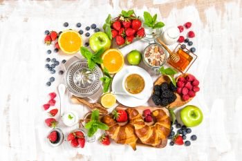 Healthy breakfast with coffee, croissants, muesli, milk, fresh berries, fruits. Top view