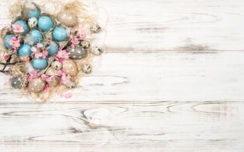Easter decoration with blue eggs and pink flowers on bright wooden background