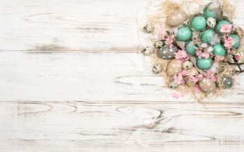 Easter decoration with eggs and flowers on bright wooden background