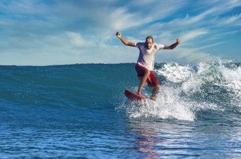 Male surfer on a blue wave at sunny day