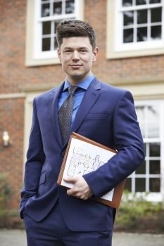 Portrait of male estate agent standing outside house