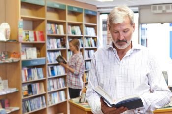 Customers Browsing Books In Bookshop
