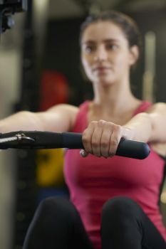 Young Woman In Gym Exercising On Rowing Machine